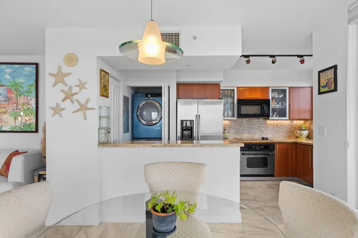 Open kitchen with Italian cabinetry, granite countertops, stainless steel appliances, and a breakfast bar overlooking the dining and living areas.