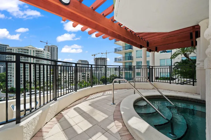 Outdoor hot tub set beneath a pergola, offering a relaxing retreat with surrounding skyline views.