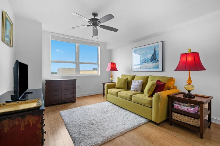 Guest bedroom with bamboo flooring, a large window, and flexible space for guests, a home office, or den.