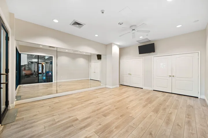 Dedicated studio for yoga, stretching, and private fitness routines, featuring mirrored walls and wood-style flooring.