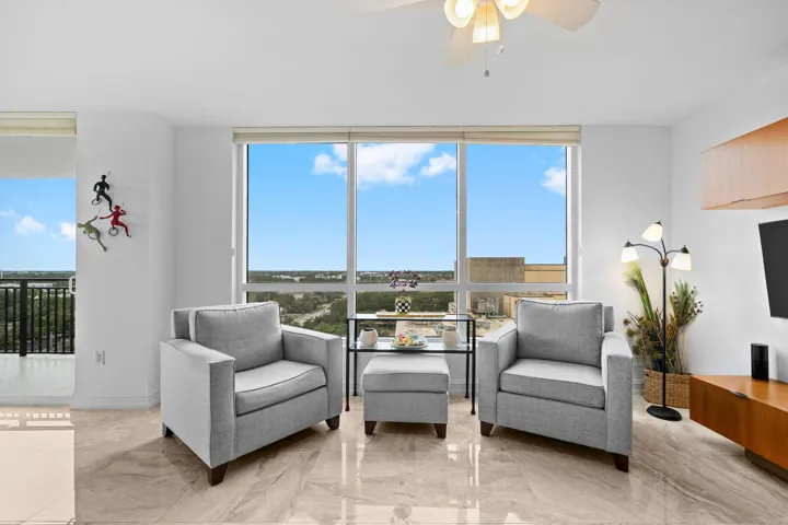 Comfortable seating area surrounded by large windows and open views, with marble flooring carried throughout.