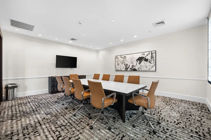 Well-appointed conference room with a large meeting table, guest seating, and wall-mounted television for work or presentations.