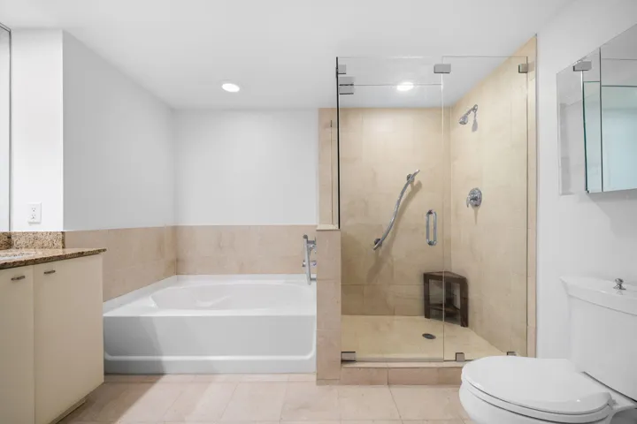 Granite vanity and mirrored wall complement the soaking tub and spacious glass-enclosed shower.