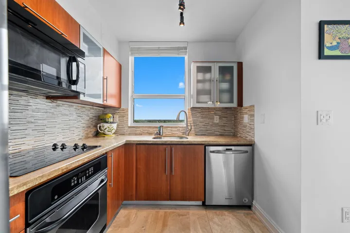 Well-appointed kitchen featuring Italian cabinetry, granite countertops, stainless steel appliances, tile backsplash, and a window over the sink.