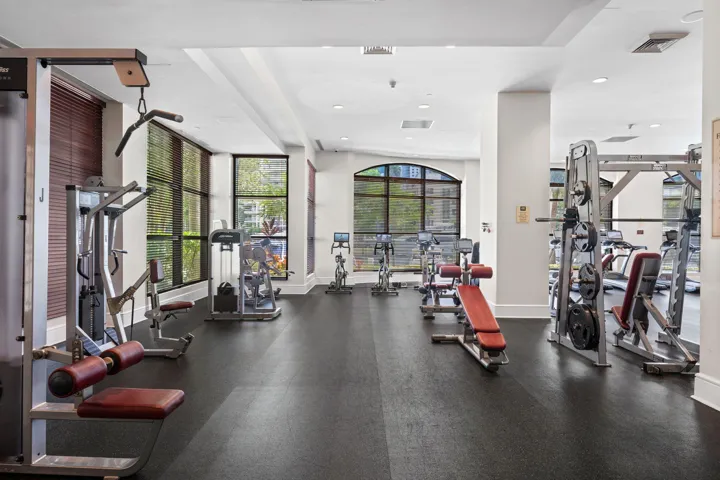 Spacious fitness center with a broad selection of strength-training equipment, cardio machines, and natural light.