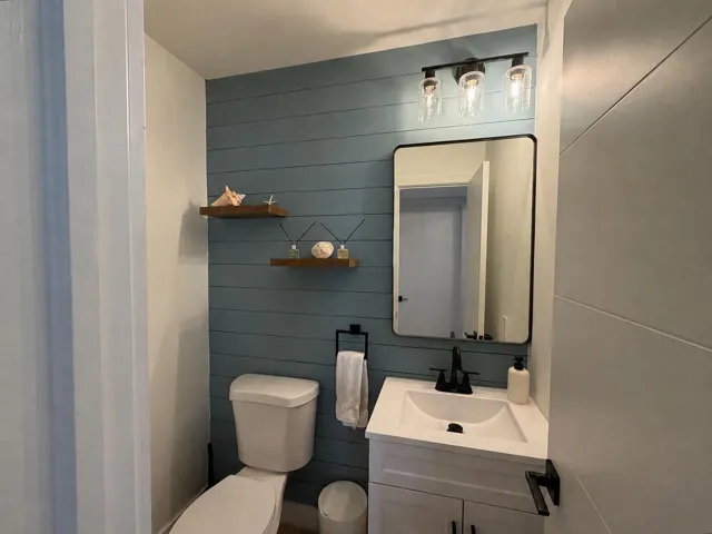 Half bathroom: shiplap wall + wood shelves for decor.