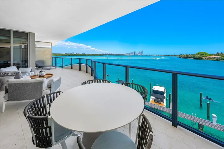 Expansive covered terrace featuring large-format tile flooring and a sleek metal railing system overlooking the water