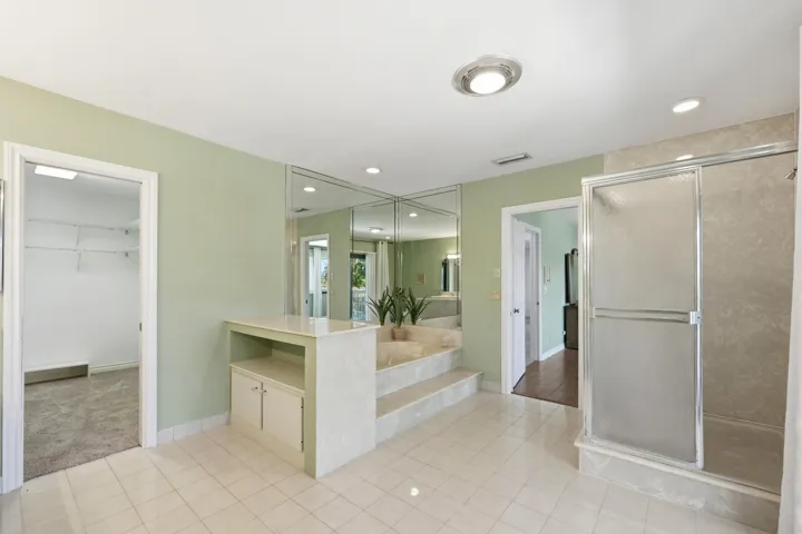 Oversized primary bathroom with dual vanities, jacuzzi tub, separate shower, bidet and impact slider to primary suite balcony.
