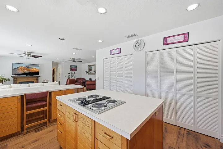 Well appointed kitchen features wood cabinetry, generous storage, dual pantry closets, breakfast bar, pass-through to outdoor entertaining spaces.