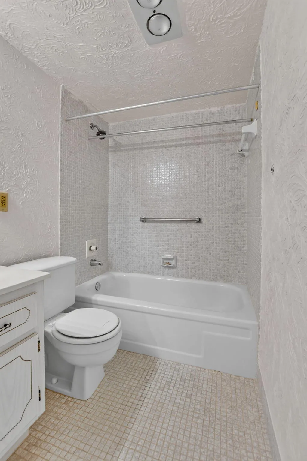 Primary en suite features neutral tiles and grab bars for extra safety.