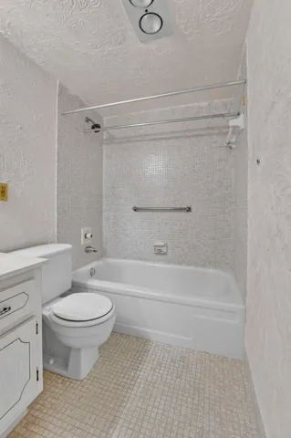 Primary en suite features neutral tiles and grab bars for extra safety.