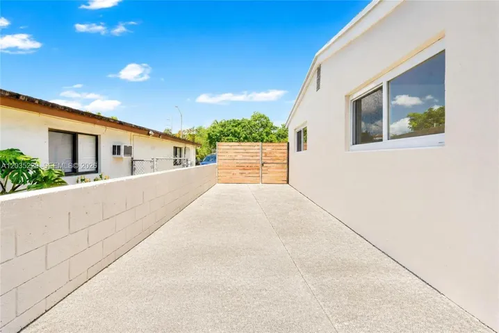 Long gated side driveway with a modern wood privacy gate and block wall — offering secure parking for a boat and easy backyard access.