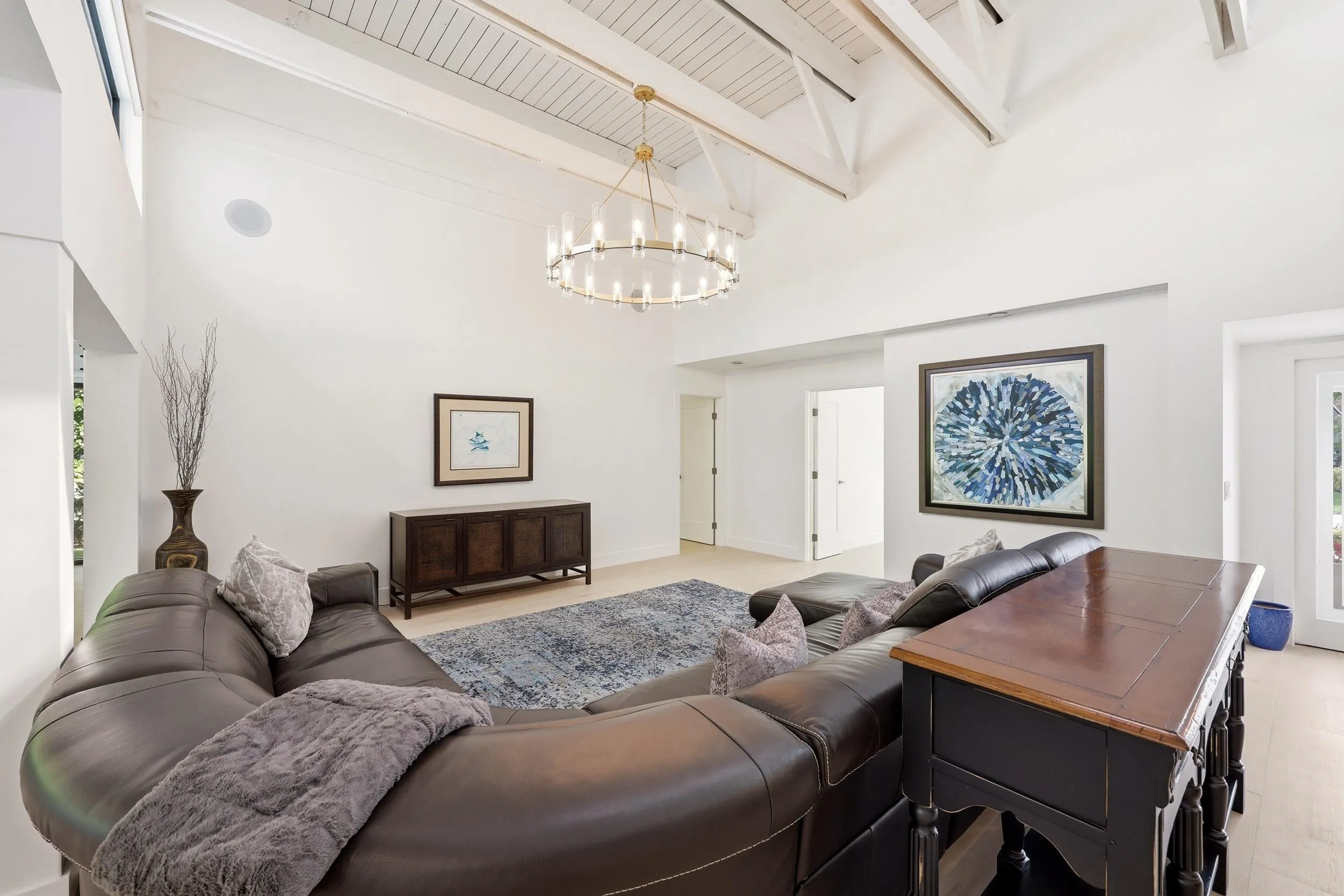 The heart of the home is an impressive open-concept living space defined by soaring vaulted ceilings, exposed beams, skylights, and an abundance of natural light. Designed for both everyday living and entertaining, the expansive great room flows seamlessly into the chef's kitchen and dining areas, while custom built-in cabinetry, wide-plank flooring, and walls of glass create a sophisticated yet inviting atmosphere throughout.