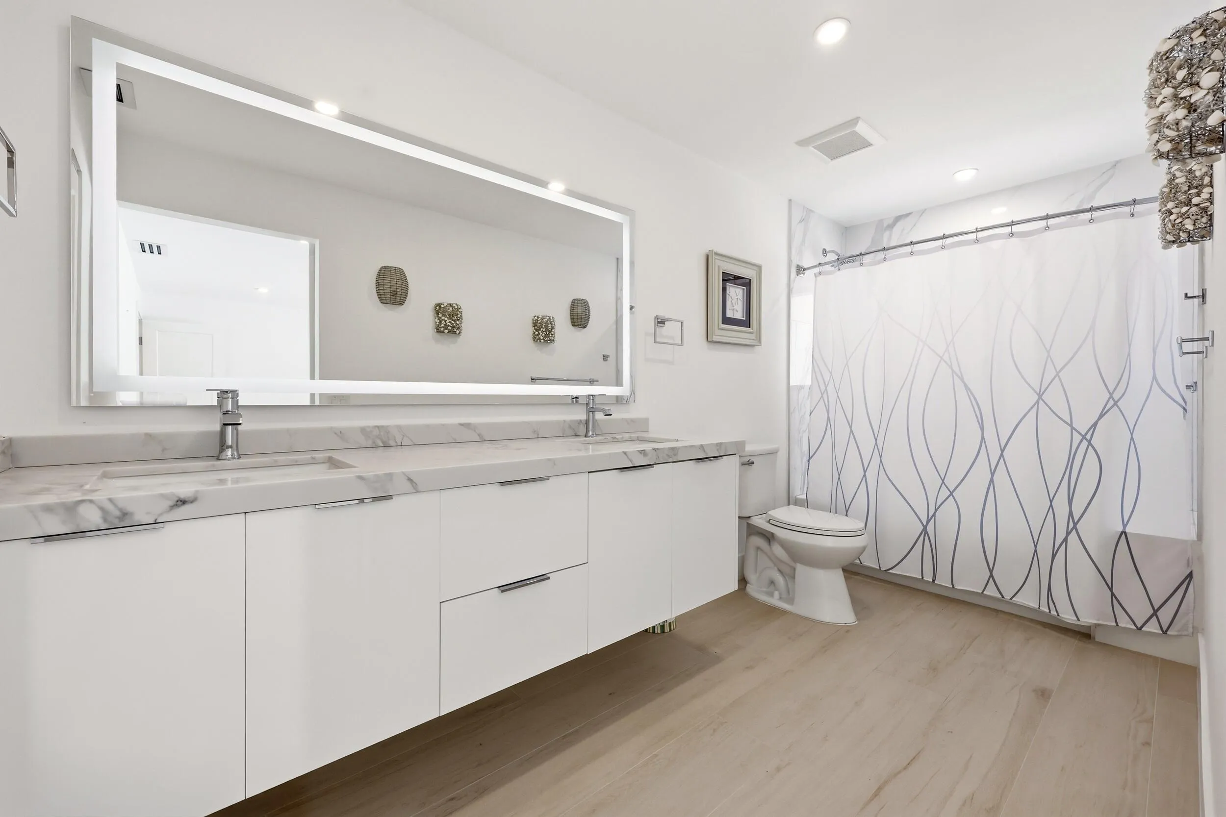 Beautifully updated with a sleek contemporary design, this spacious guest bathroom features an oversized floating vanity with dual sinks, quartz countertops, an illuminated designer mirror, and elegant marble-look tile accents. The full tub and shower combination offers both style and functionality, creating a comfortable and inviting retreat for family and guests alike.