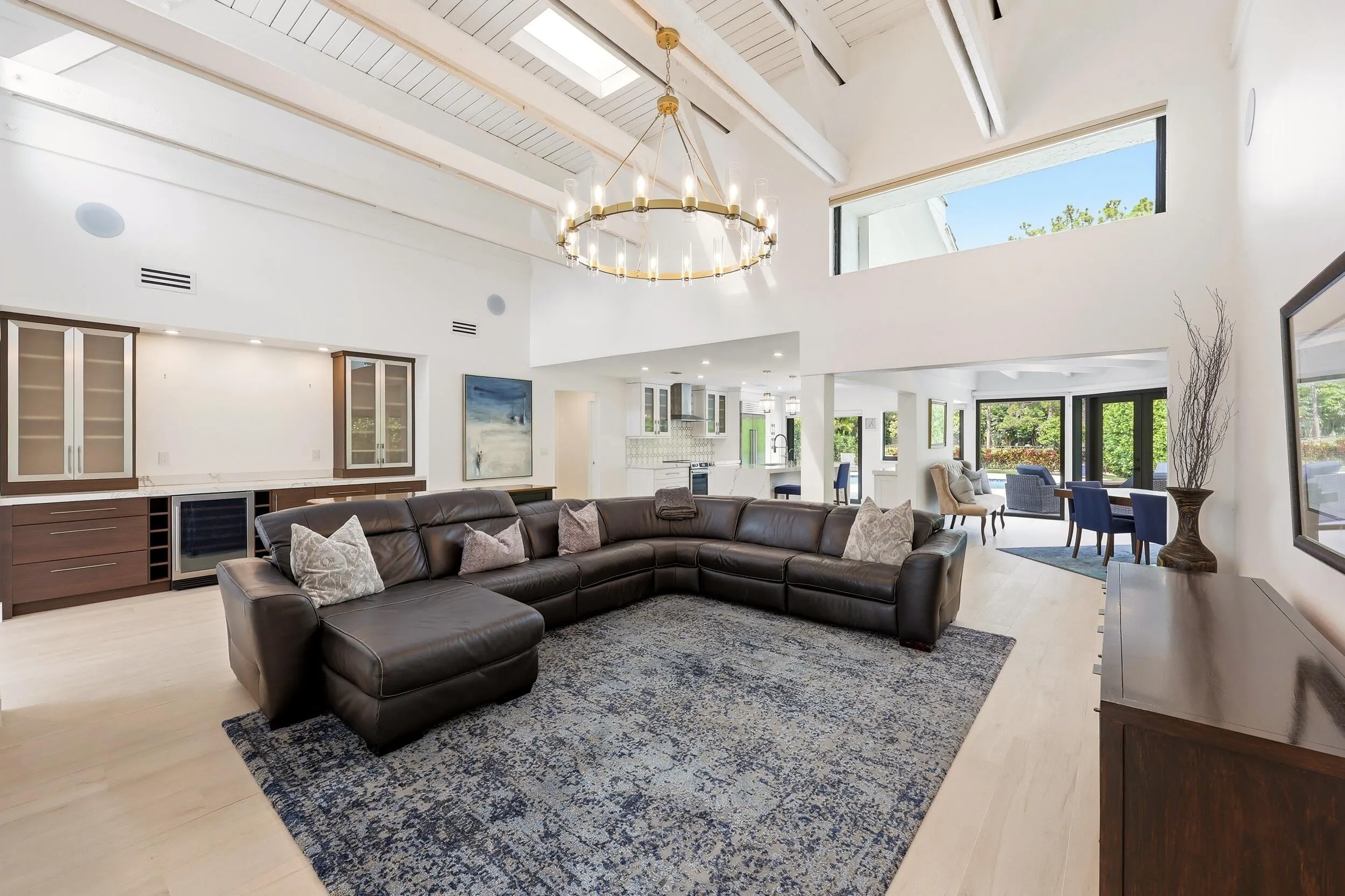The heart of the home is an extraordinary open concept living space where soaring vaulted ceilings, exposed wood beams, skylights, and walls of hurricane impact glass fill the interior with natural light. Thoughtfully designed for both everyday living and effortless entertaining, the great room flows seamlessly into the dining area and chef's kitchen, creating a true indoor outdoor lifestyle.