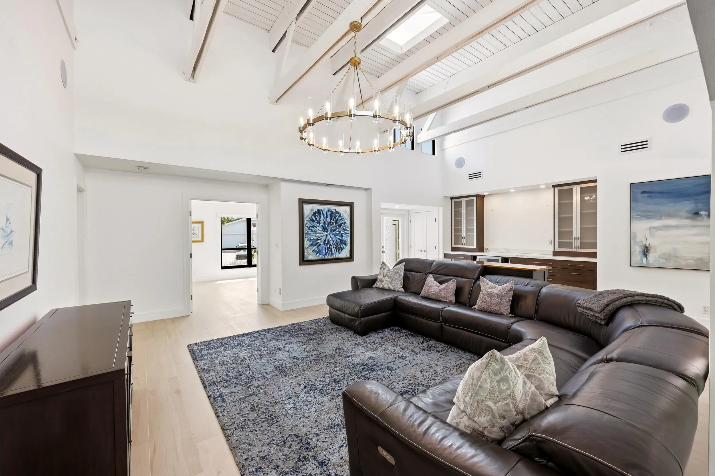 The heart of the home is an extraordinary open concept living space where soaring vaulted ceilings, exposed wood beams, skylights, and walls of hurricane impact glass fill the interior with natural light. Thoughtfully designed for both everyday living and effortless entertaining, the great room flows seamlessly into the dining area and chef's kitchen, creating a true indoor outdoor lifestyle.