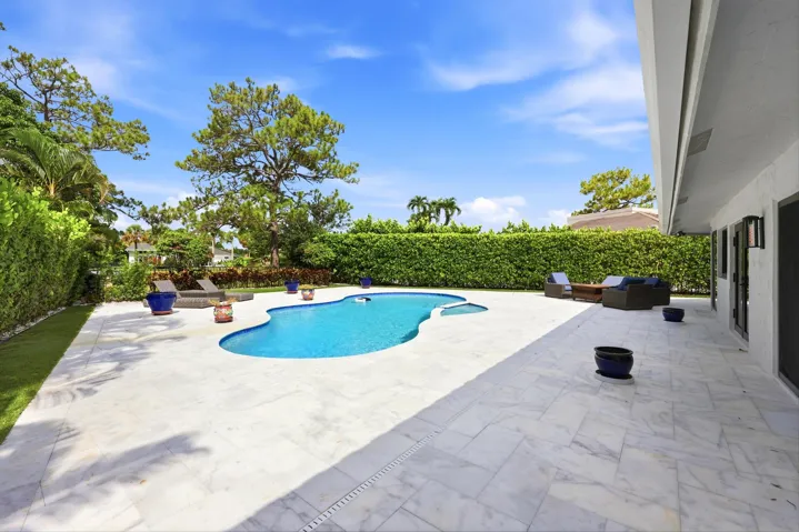 Discover your own private backyard sanctuary where modern luxury meets the natural beauty of Old Florida. Backing directly to a nature preserve, this extraordinary outdoor retreat offers a level of privacy rarely found in South Florida, creating a peaceful setting with no rear neighbors and lush tropical views in every direction. A newly renovated freeform pool and spa are surrounded by an expansive marble pool deck, offering the perfect backdrop for relaxing afternoons or effortless entertaining.Thoughtfully designed as an extension of the home, the backyard features multiple spaces to lounge, dine, and gather, all immersed in the serenity of the surrounding preserve. Whether enjoying your morning coffee, an evening swim, or hosting friends and family, every moment is enhanced by the tranquil landscape and exceptional sense of seclusion that defines this remarkable property.