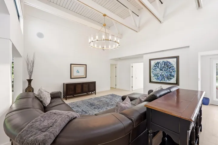 The heart of the home is an impressive open-concept living space defined by soaring vaulted ceilings, exposed beams, skylights, and an abundance of natural light. Designed for both everyday living and entertaining, the expansive great room flows seamlessly into the chef's kitchen and dining areas, while custom built-in cabinetry, wide-plank flooring, and walls of glass create a sophisticated yet inviting atmosphere throughout.
