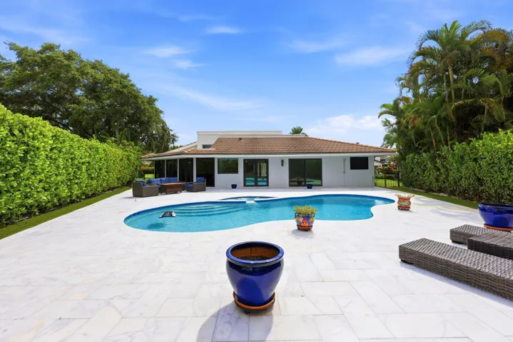 Discover your own private backyard sanctuary where modern luxury meets the natural beauty of Old Florida. Backing directly to a nature preserve, this extraordinary outdoor retreat offers a level of privacy rarely found in South Florida, creating a peaceful setting with no rear neighbors and lush tropical views in every direction. A newly renovated freeform pool and spa are surrounded by an expansive marble pool deck, offering the perfect backdrop for relaxing afternoons or effortless entertaining.Thoughtfully designed as an extension of the home, the backyard features multiple spaces to lounge, dine, and gather, all immersed in the serenity of the surrounding preserve. Whether enjoying your morning coffee, an evening swim, or hosting friends and family, every moment is enhanced by the tranquil landscape and exceptional sense of seclusion that defines this remarkable property.