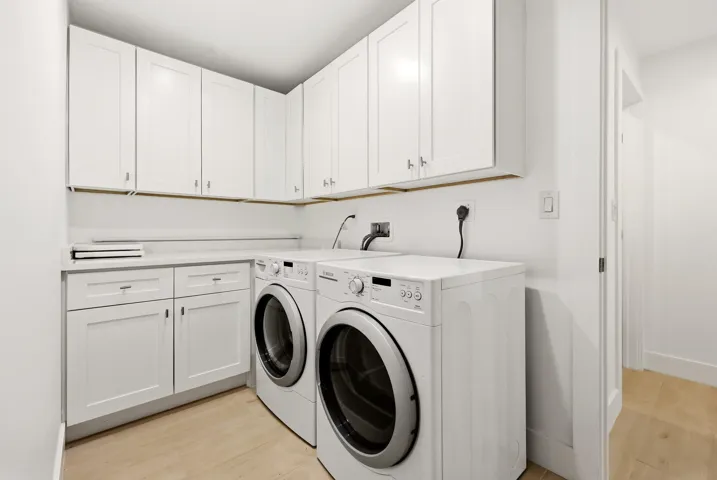 Thoughtfully designed for everyday convenience, the spacious laundry room features abundant custom cabinetry, extensive countertop workspace for folding and organization, and full-size front-loading washer and dryer. Clean, modern finishes and ample storage make this highly functional space as practical as it is attractive.