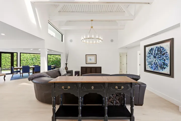 The heart of the home is an impressive open-concept living space defined by soaring vaulted ceilings, exposed beams, skylights, and an abundance of natural light. Designed for both everyday living and entertaining, the expansive great room flows seamlessly into the chef's kitchen and dining areas, while custom built-in cabinetry, wide-plank flooring, and walls of glass create a sophisticated yet inviting atmosphere throughout.