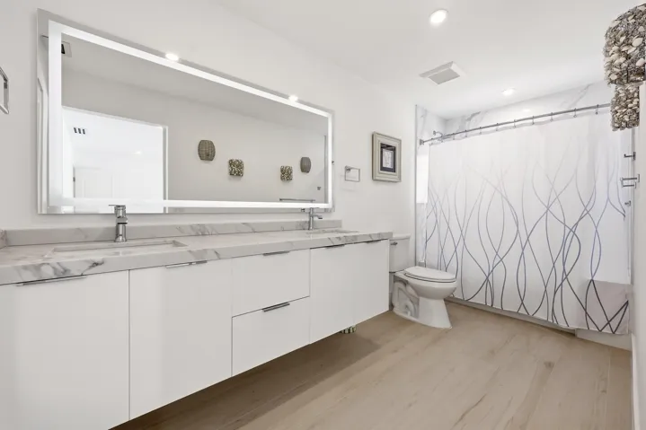 Beautifully updated with a sleek contemporary design, this spacious guest bathroom features an oversized floating vanity with dual sinks, quartz countertops, an illuminated designer mirror, and elegant marble-look tile accents. The full tub and shower combination offers both style and functionality, creating a comfortable and inviting retreat for family and guests alike.