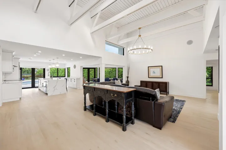 The heart of the home is an extraordinary open concept living space where soaring vaulted ceilings, exposed wood beams, skylights, and walls of hurricane impact glass fill the interior with natural light. Thoughtfully designed for both everyday living and effortless entertaining, the great room flows seamlessly into the dining area and chef's kitchen, creating a true indoor outdoor lifestyle.