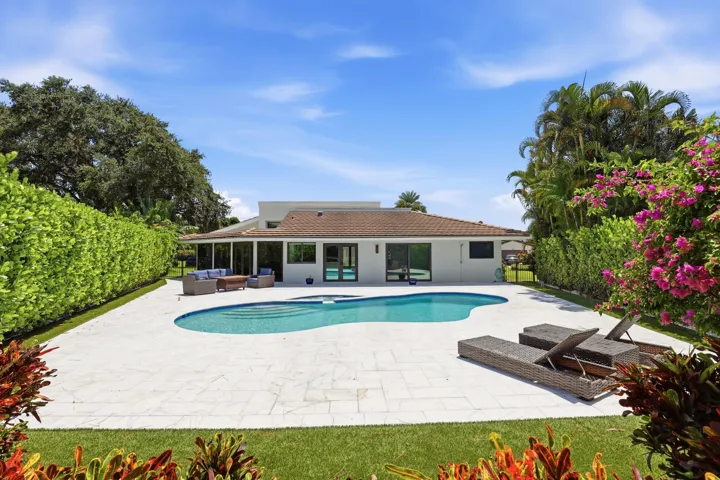 Discover your own private backyard sanctuary where modern luxury meets the natural beauty of Old Florida. Backing directly to a nature preserve, this extraordinary outdoor retreat offers a level of privacy rarely found in South Florida, creating a peaceful setting with no rear neighbors and lush tropical views in every direction. A newly renovated freeform pool and spa are surrounded by an expansive marble pool deck, offering the perfect backdrop for relaxing afternoons or effortless entertaining.Thoughtfully designed as an extension of the home, the backyard features multiple spaces to lounge, dine, and gather, all immersed in the serenity of the surrounding preserve. Whether enjoying your morning coffee, an evening swim, or hosting friends and family, every moment is enhanced by the tranquil landscape and exceptional sense of seclusion that defines this remarkable property.