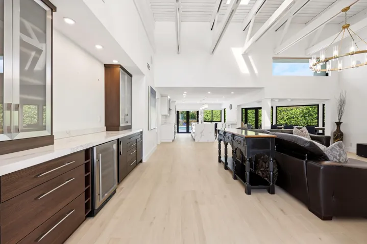 The heart of the home is an extraordinary open concept living space where soaring vaulted ceilings, exposed wood beams, skylights, and walls of hurricane impact glass fill the interior with natural light. Thoughtfully designed for both everyday living and effortless entertaining, the great room flows seamlessly into the dining area and chef's kitchen, creating a true indoor outdoor lifestyle.