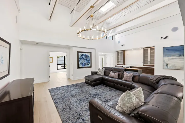 The heart of the home is an extraordinary open concept living space where soaring vaulted ceilings, exposed wood beams, skylights, and walls of hurricane impact glass fill the interior with natural light. Thoughtfully designed for both everyday living and effortless entertaining, the great room flows seamlessly into the dining area and chef's kitchen, creating a true indoor outdoor lifestyle.