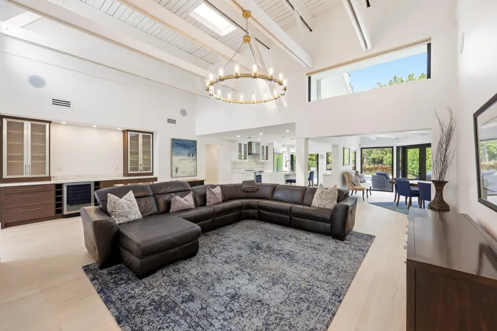 The heart of the home is an extraordinary open concept living space where soaring vaulted ceilings, exposed wood beams, skylights, and walls of hurricane impact glass fill the interior with natural light. Thoughtfully designed for both everyday living and effortless entertaining, the great room flows seamlessly into the dining area and chef's kitchen, creating a true indoor outdoor lifestyle.