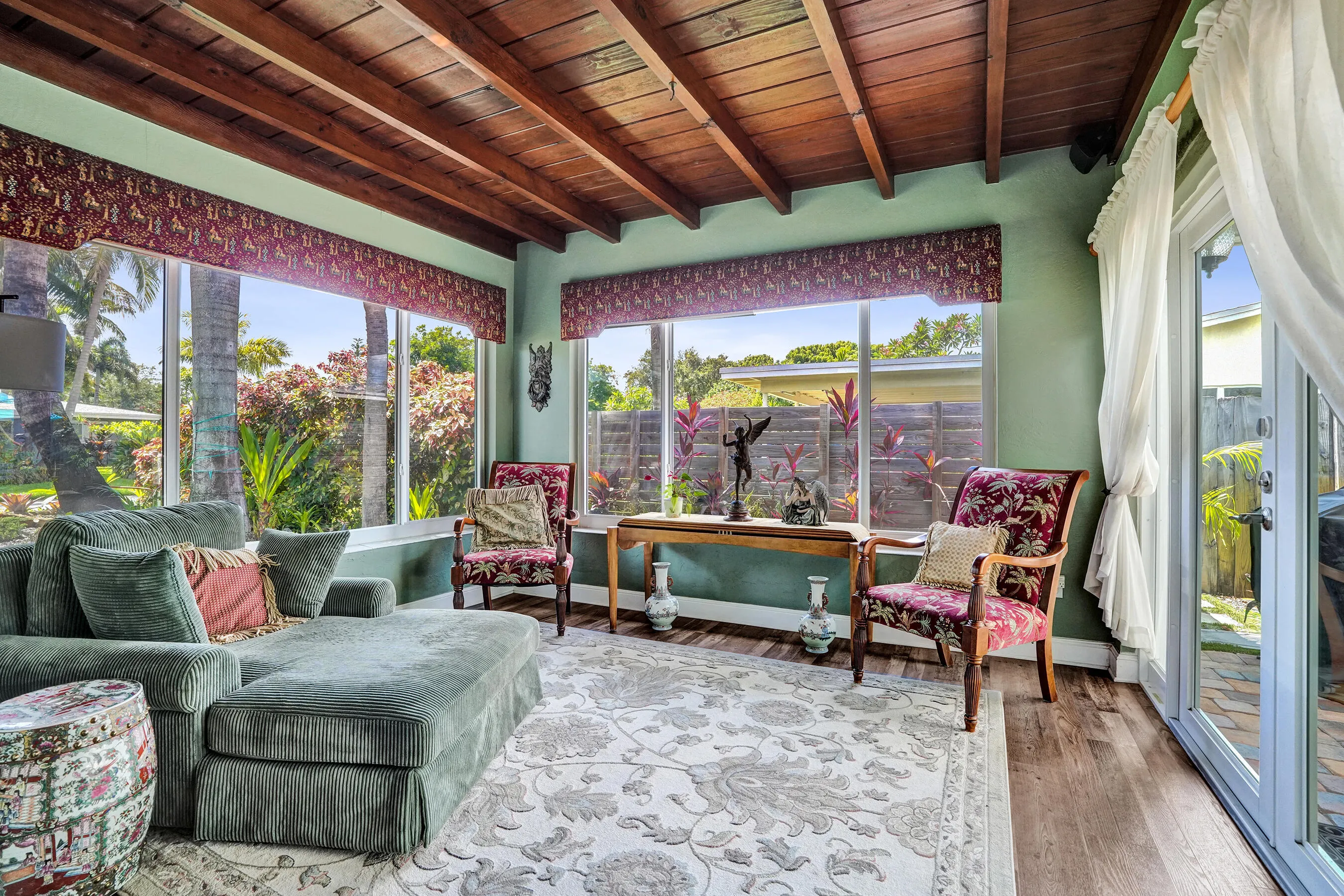 Bright Florida room featuring exposed wood beams, tongue-and-groove ceiling, French doors, and seamless indoor-outdoor living. This room has that special Charm!