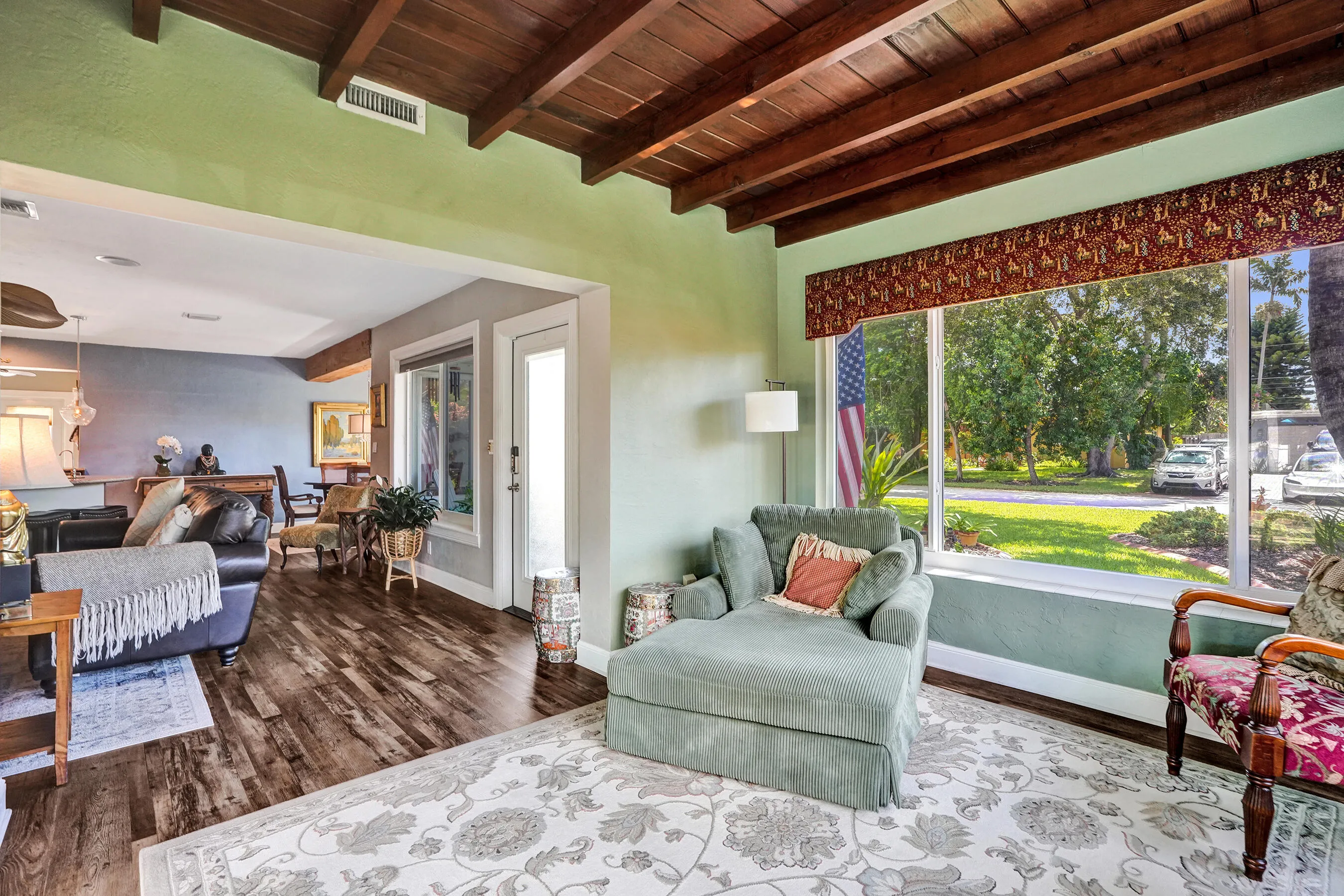Bright Florida room featuring exposed wood beams, tongue-and-groove ceiling, French doors, and seamless indoor-outdoor living. This room has that special Charm!
