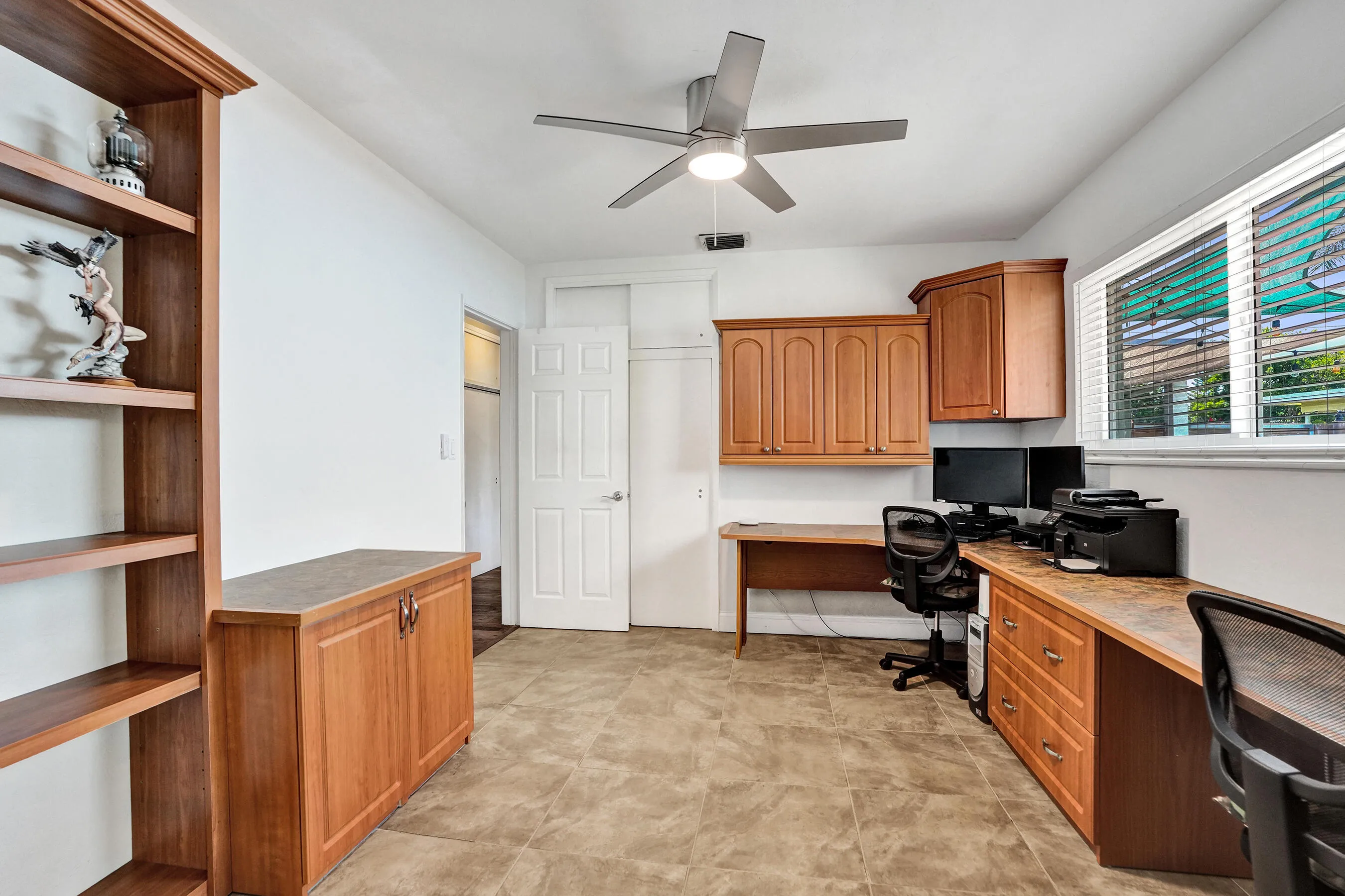 Flexible office or fourth bedroom featuring custom built-in cabinetry, desk, bookshelves, ample storage, and an original closet.