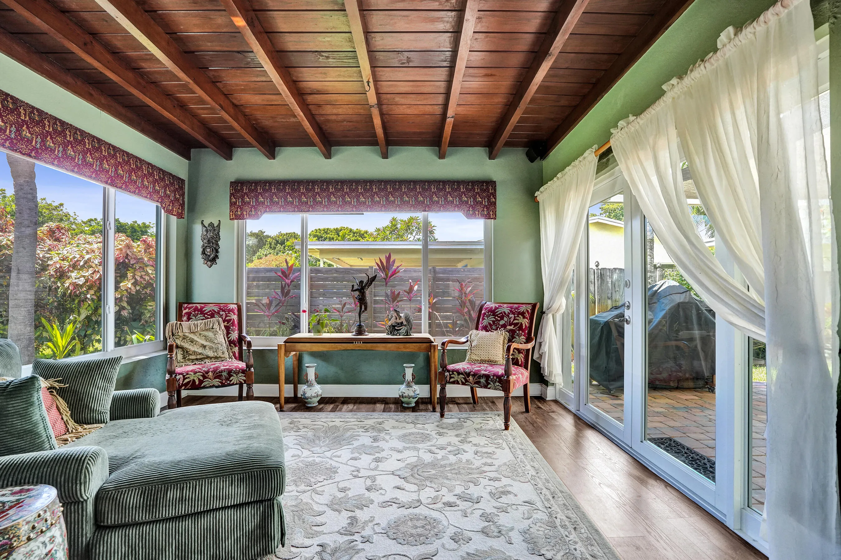 Bright Florida room featuring exposed wood beams, tongue-and-groove ceiling, French doors, and seamless indoor-outdoor living. This room has that special Charm!
