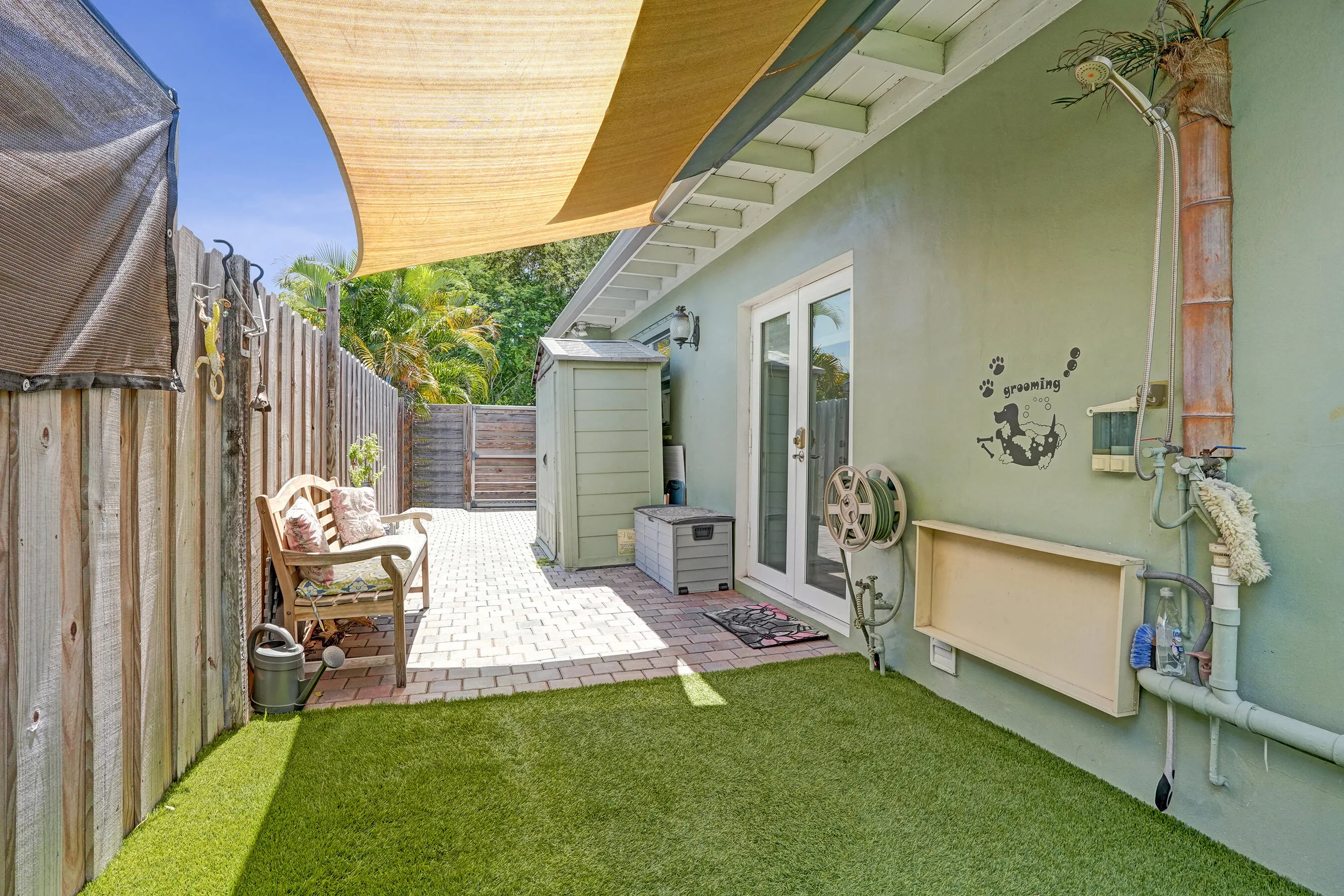 Private side yard featuring pet-friendly turf and a convenient outdoor wash station—perfect for rinsing off pets, kids, or after gardening.