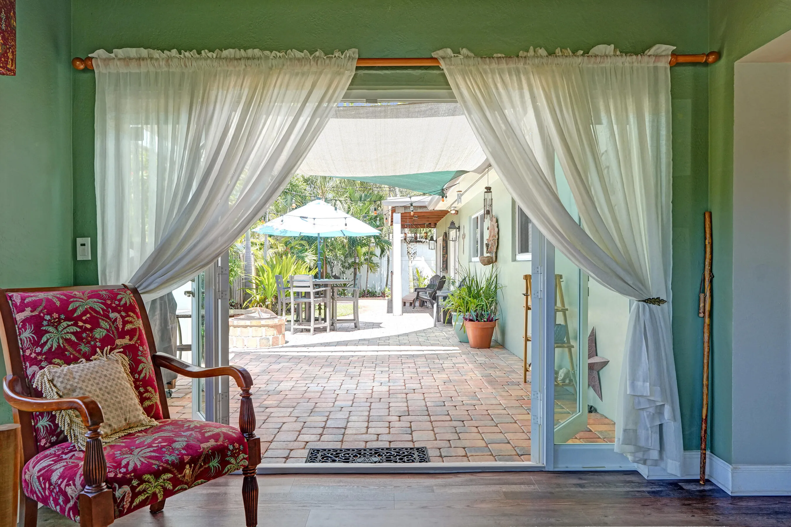 Bright Florida room featuring exposed wood beams, tongue-and-groove ceiling, French doors, and seamless indoor-outdoor living. This room has that special Charm!