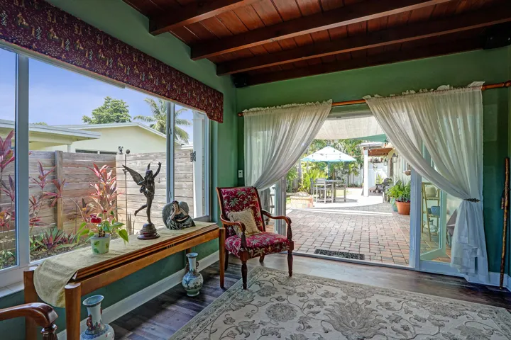 Bright Florida room featuring exposed wood beams, tongue-and-groove ceiling, French doors, and seamless indoor-outdoor living. This room has that special Charm!