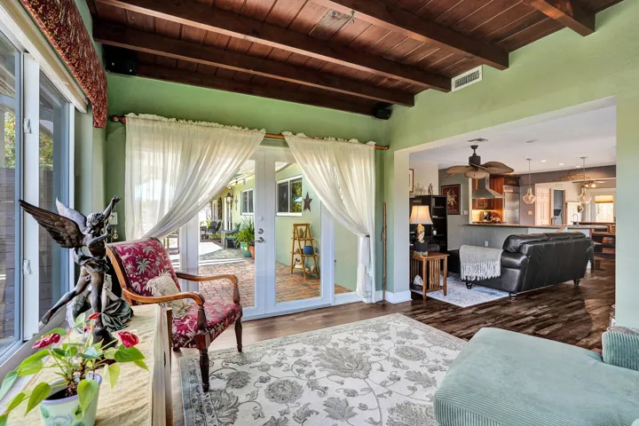 Bright Florida room featuring exposed wood beams, tongue-and-groove ceiling, French doors, and seamless indoor-outdoor living. This room has that special Charm!