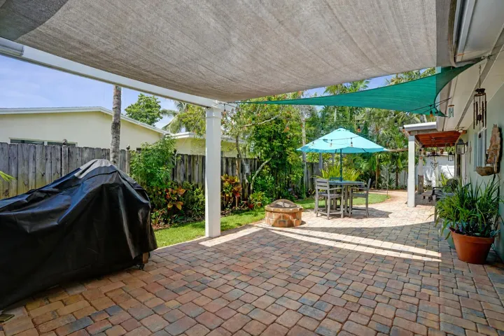 Resort-style outdoor entertaining area with built-in gas fire pit, multiple seating areas, and beautifully landscaped surroundings.