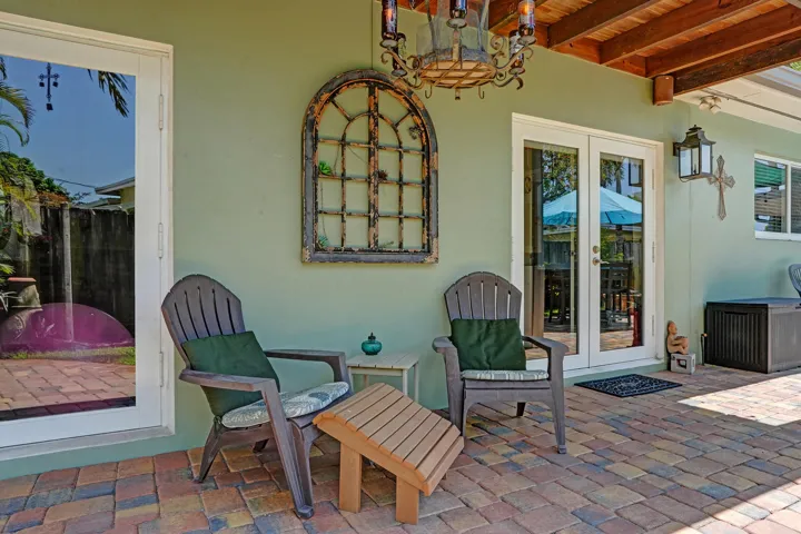 Private tropical backyard featuring lush landscaping, brick paver courtyard, built-in gas fire pit, New Orleans copper gas lanterns, and pet-friendly turf.
