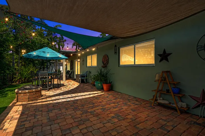 Authentic New Orleans copper gas coach lanterns, brick paver patio, lush tropical landscaping, and a true resort-style outdoor retreat.