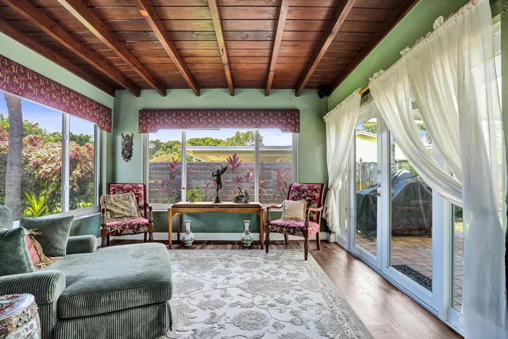 Bright Florida room featuring exposed wood beams, tongue-and-groove ceiling, French doors, and seamless indoor-outdoor living. This room has that special Charm!