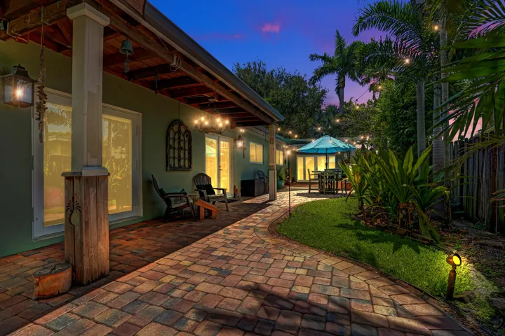 Authentic New Orleans copper gas coach lanterns, brick paver patio, lush tropical landscaping, and a true resort-style outdoor retreat.