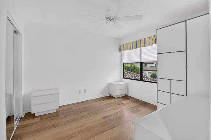 Bright & inviting guest bedroom featuring a large window, generous closet space, & wood-look flooring.