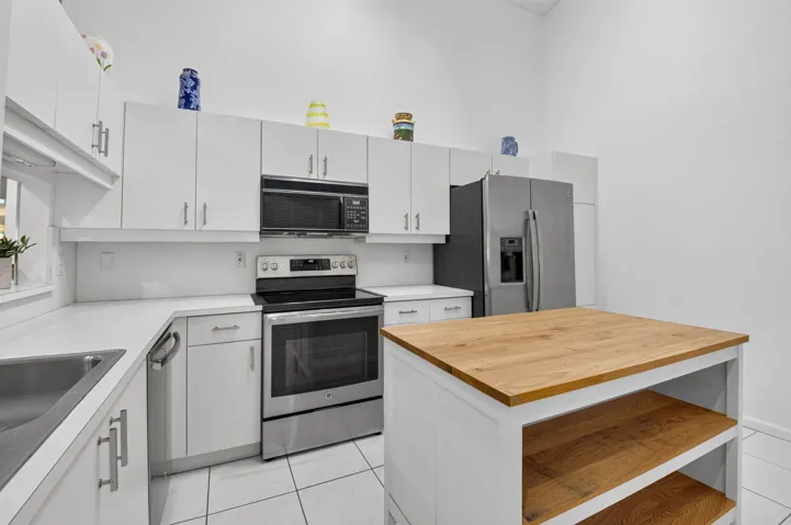 White cabinetry, stainless appliances, & moveable kitchen block island.