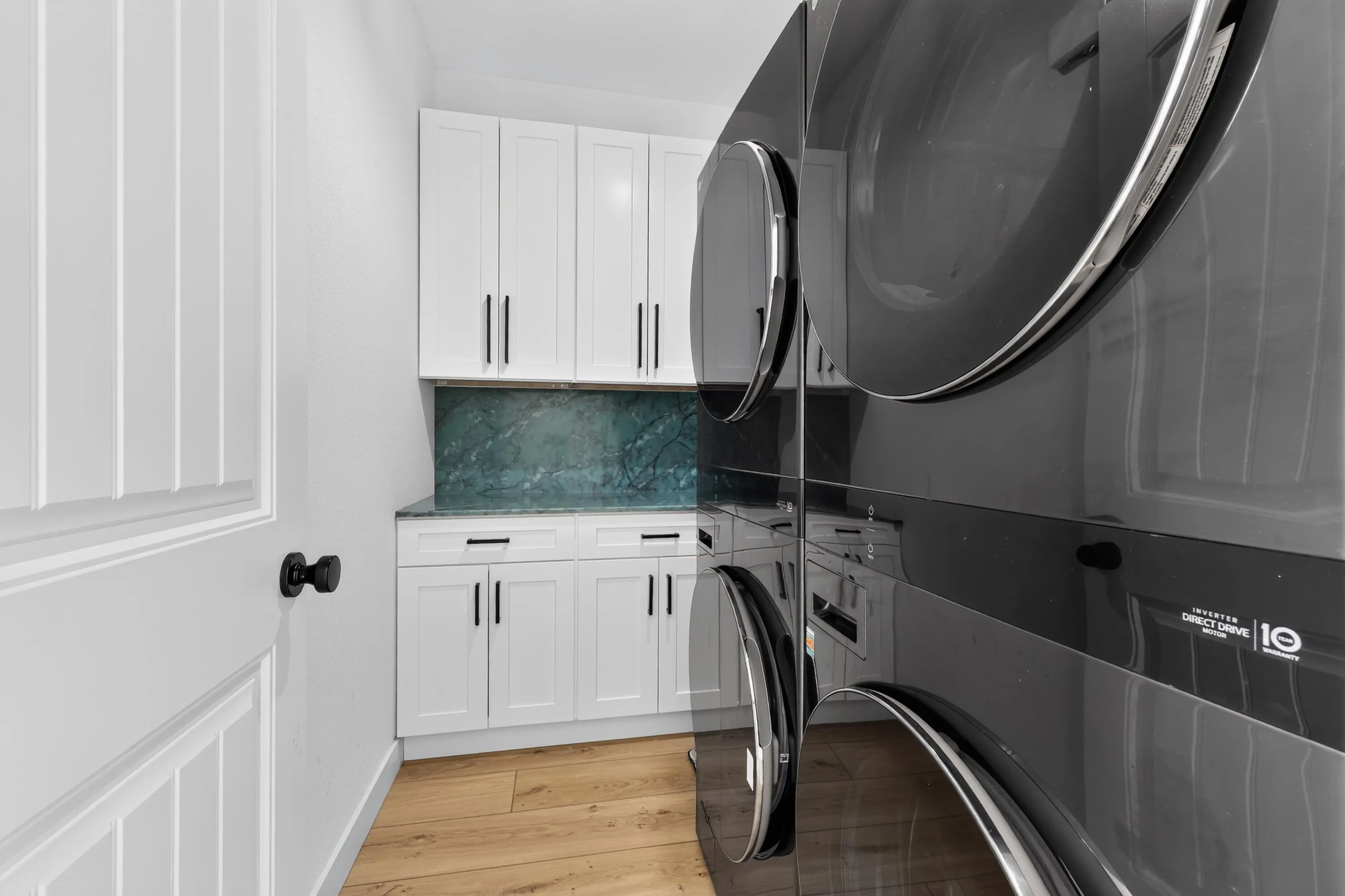 Laundry room featuring double washers and dryers, folding station and storage and cabinets
