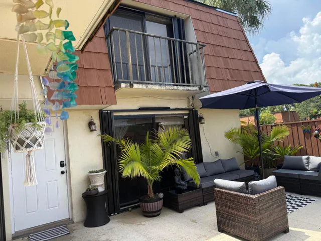 Ground-level patio featuring concrete flooring, a privacy fence, accordion shutters