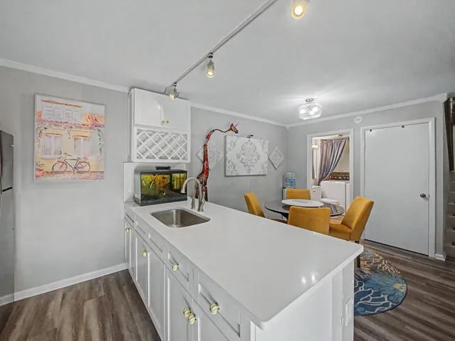 Kitchen featuring white shaker cabinetry, an integrated wine rack, and a stainless steel sink