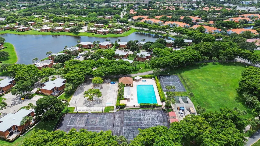 Aerial perspective showcasing multiple residential buildings, a central aquatic facility with a rectangular pool, and tennis courts